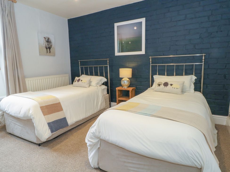 A bedroom with two beds and a lamp on a nightstand at The Brew House in Bakewell