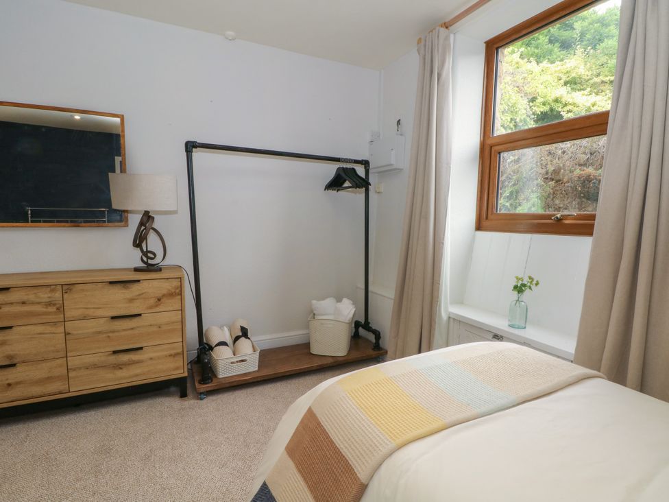 A bedroom with a dresser, lamp, and clothes rack at The Brew House in Bakewell
