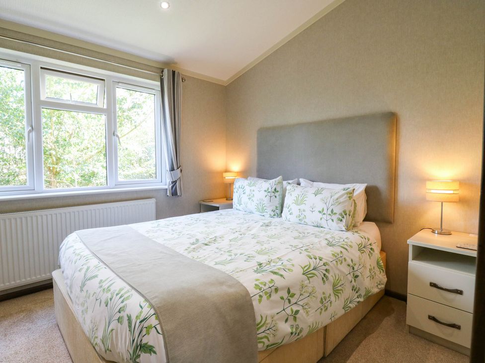 A bedroom with a bed and windows at Oak Lodge Battisford near Stowmarket