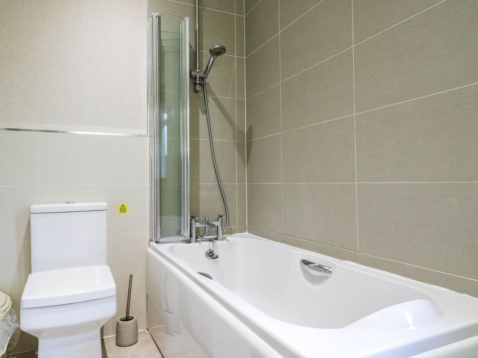 A bathroom with a bathtub and toilet at Oak Lodge in Battisford near Stowmarket