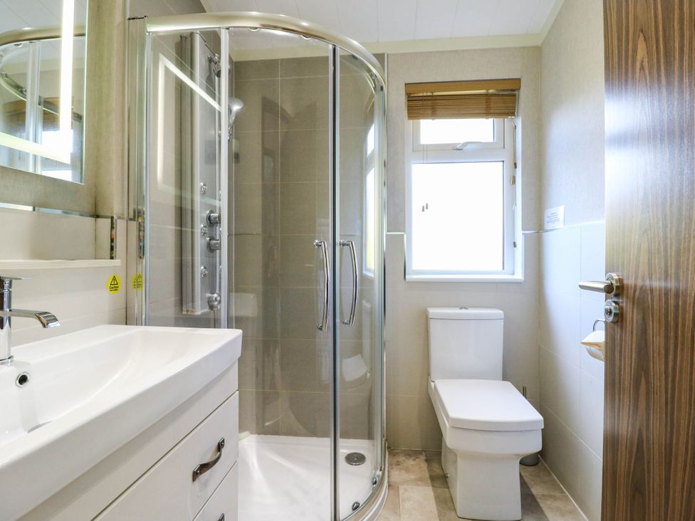 A bathroom with a shower, sink, and toilet at Oak Lodge in Battisford near Stowmarket