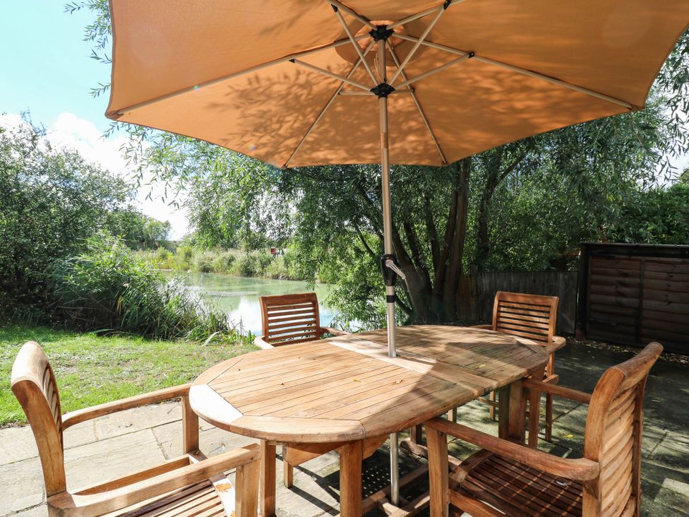 A garden area with a table and chairs under an umbrella at Oak Lodge Battisford near Stowmarket