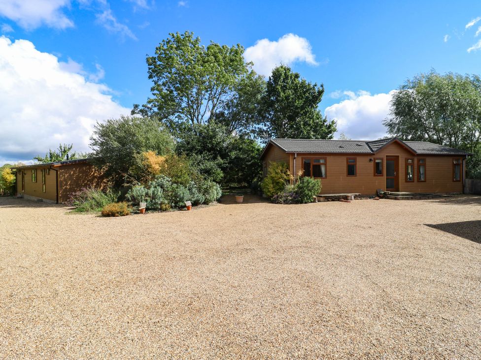 A house with gravel driveway and trees at Oak Lodge Battisford near Stowmarket