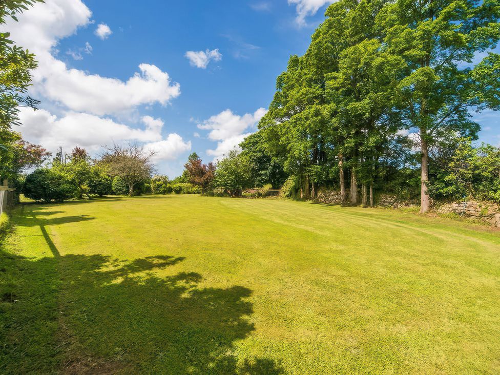 A grassy field with trees and blue sky at Cuddle Cabin in Constantine