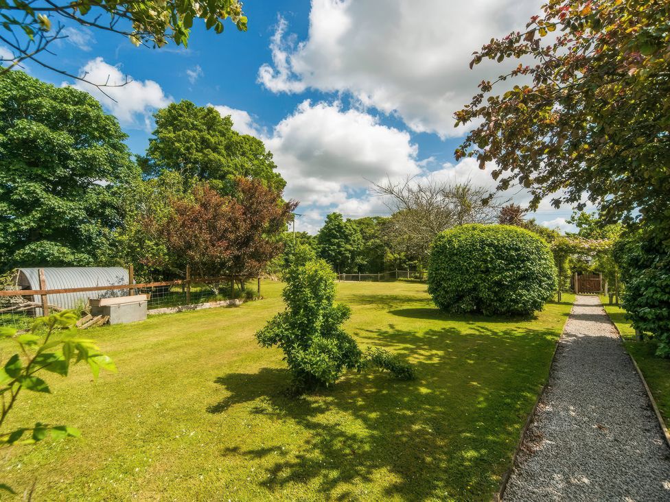 A garden with trees and a gravel path at cuddle cabin in Constantine