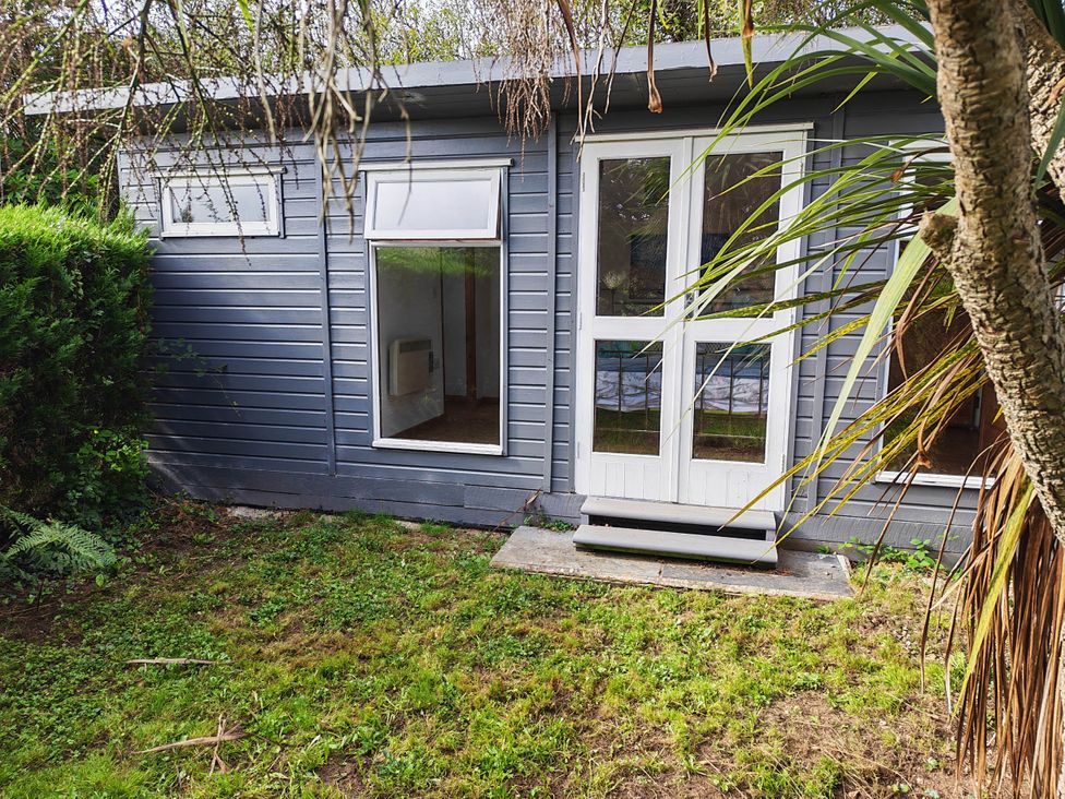 An exterior view of a wooden structure with windows and a door at Hazel Lodge in Constantine