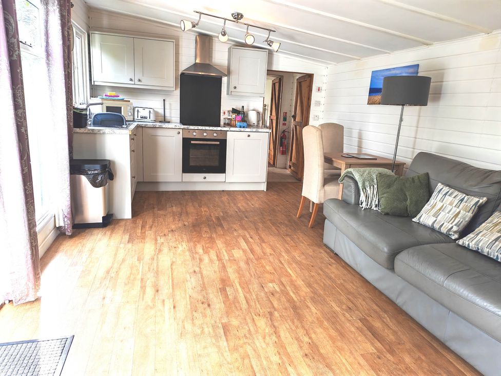 A living room with a kitchen area and seating at Hazel Lodge in Constantine