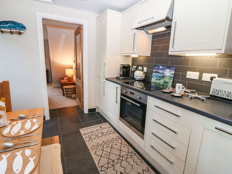 A kitchen with appliances and a dining table at Bryn Tirion - Rhosneigr