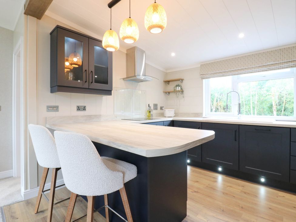 A kitchen with an island and bar stools at Cherry Lodge Battisford near Stowmarket