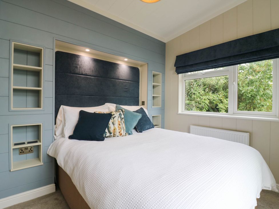 A bedroom with a bed and shelves at Cherry Lodge Battisford near Stowmarket
