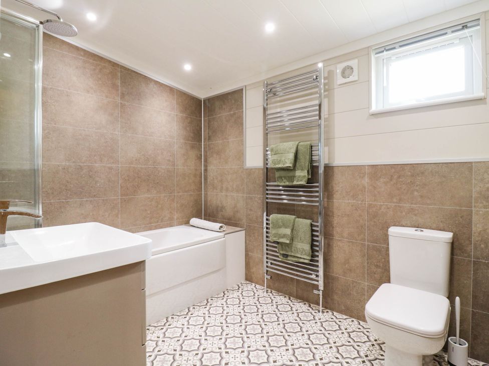 A bathroom with a bathtub, toilet, and towel radiator at Cherry Lodge in Battisford near Stowmarket