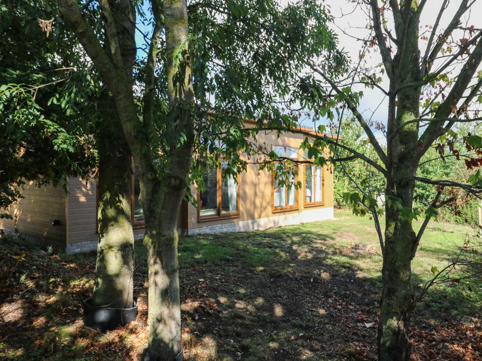 A wooden exterior structure surrounded by trees at Cherry Lodge Battisford near Stowmarket