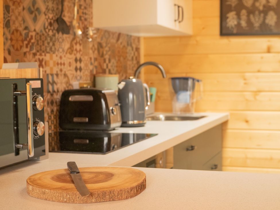 A kitchen with a cutting board and appliances at Willow Lodge in Stowmarket