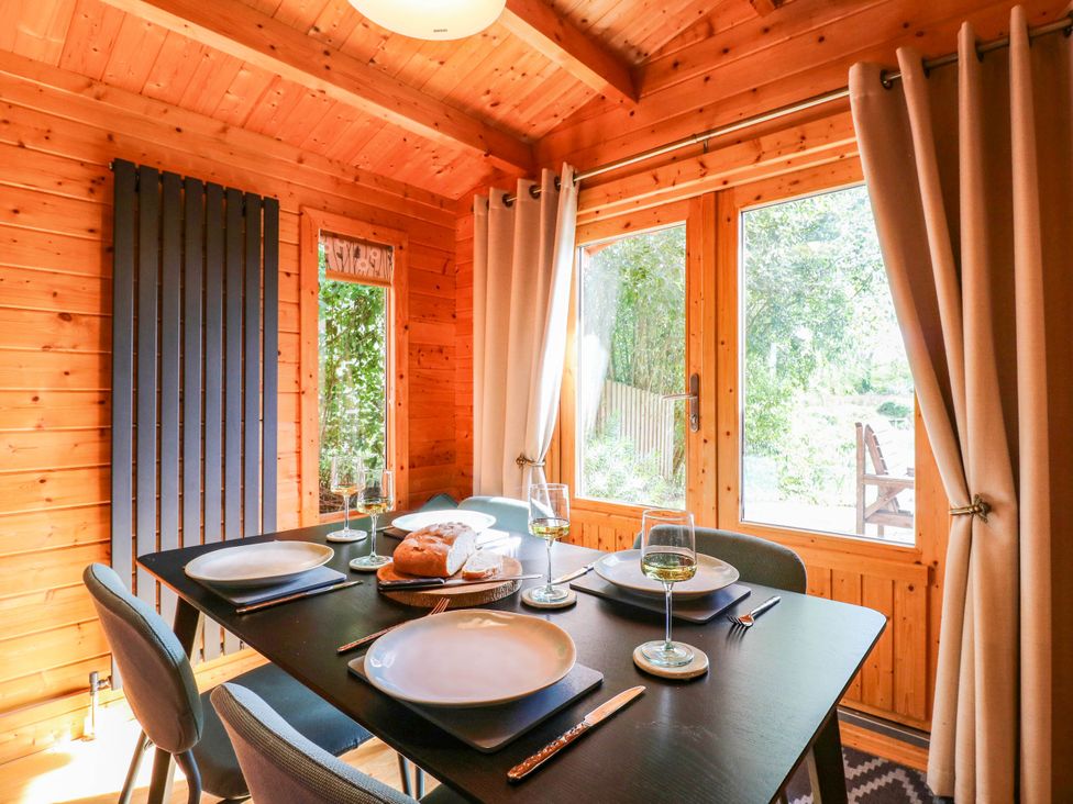 A dining room with a table set for meals at Willow Lodge in Stowmarket