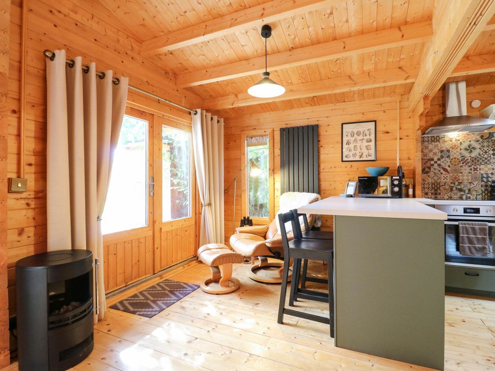 A kitchen with bar stools and a coffee maker at Willow Lodge in Stowmarket