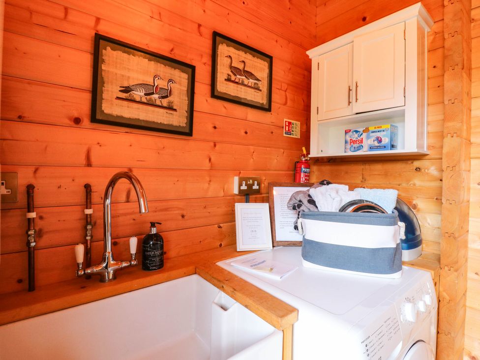 A laundry room with a washing machine and storage at Willow Lodge in Stowmarket
