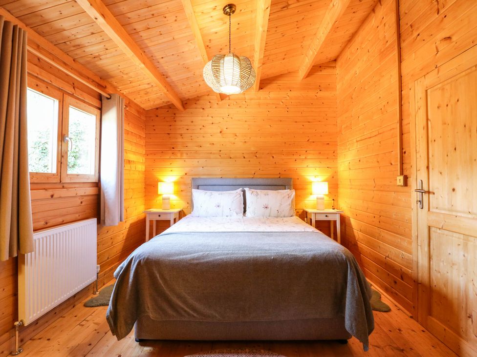 A bedroom with a bed and lamps at Willow Lodge in Stowmarket