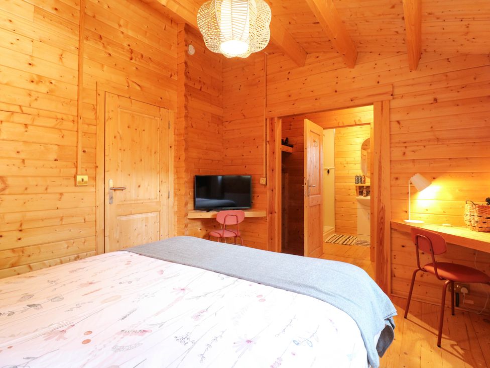 A bedroom with wooden walls and furniture at Willow Lodge in Stowmarket