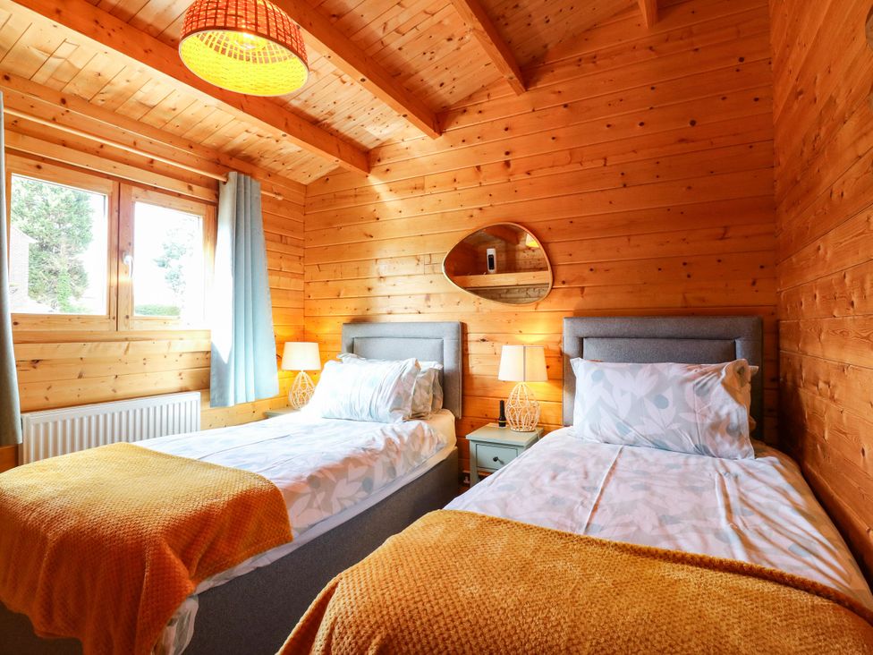 A bedroom with two beds and a mirror at Willow Lodge in Stowmarket