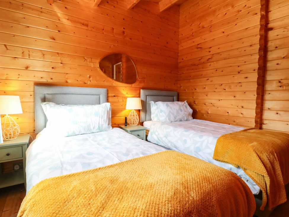 A bedroom with two single beds and lamps at Willow Lodge in Stowmarket