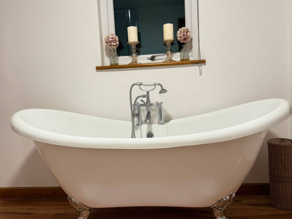 A bathroom with a bathtub and window at Willow Cottage in Constantine