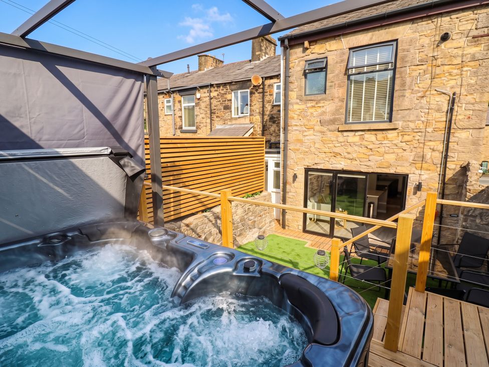 An outdoor space with a hot tub and wooden decking at 2 Makant Street Bolton