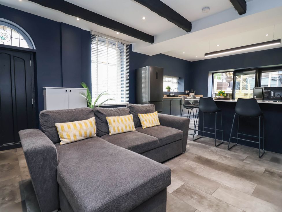 A living room with a sofa and kitchen appliances at 2 Makant Street in Bolton