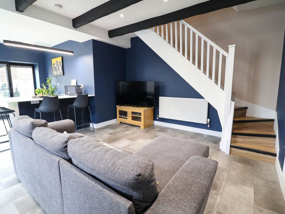 A living room with a sofa, television, and staircase at 2 Makant Street in Bolton