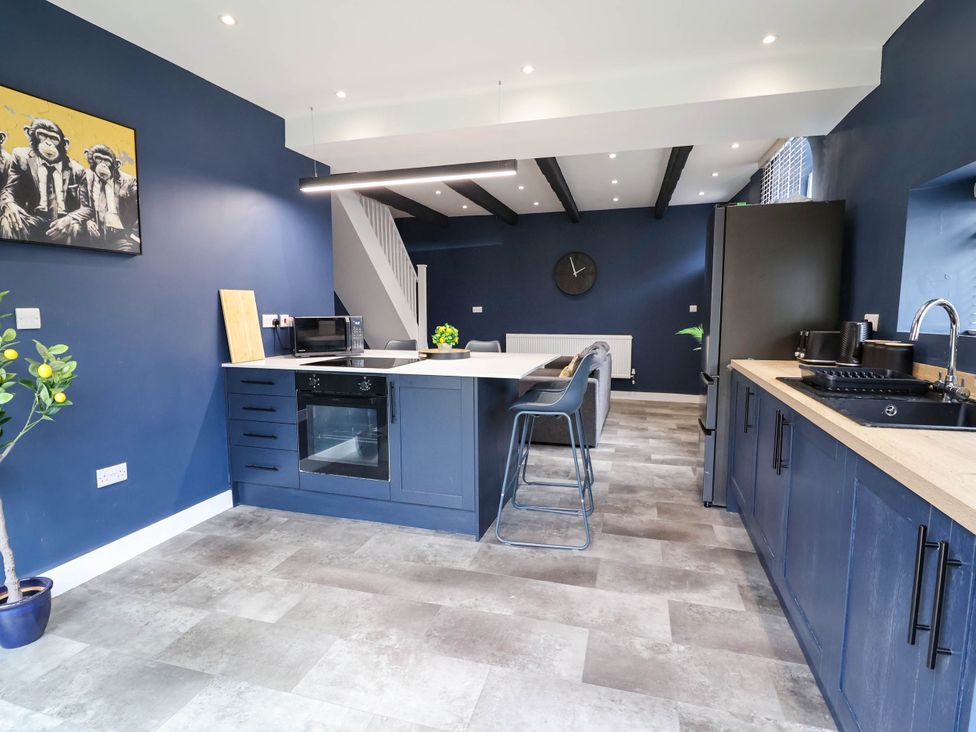 A kitchen featuring a refrigerator, microwave, sink and bar stools at 2 Makant Street in Bolton
