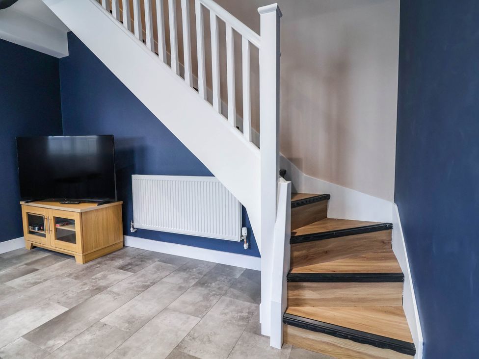 A living room with a staircase and television at 2 Makant Street in Bolton