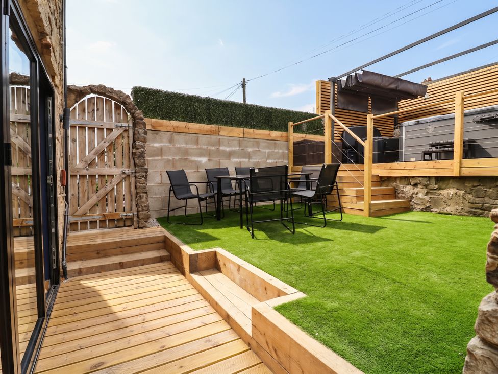 A garden with a table and chairs on artificial grass at 2 Makant Street in Bolton