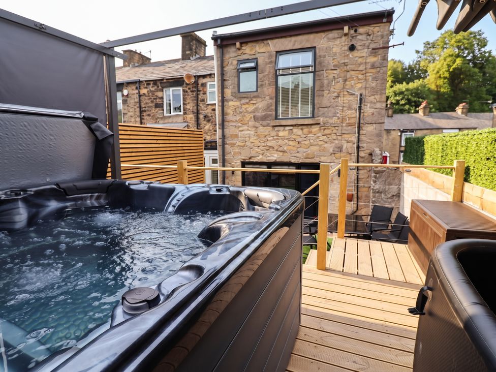 An outdoor area with a hot tub and wooden decking at 2 Makant Street Bolton