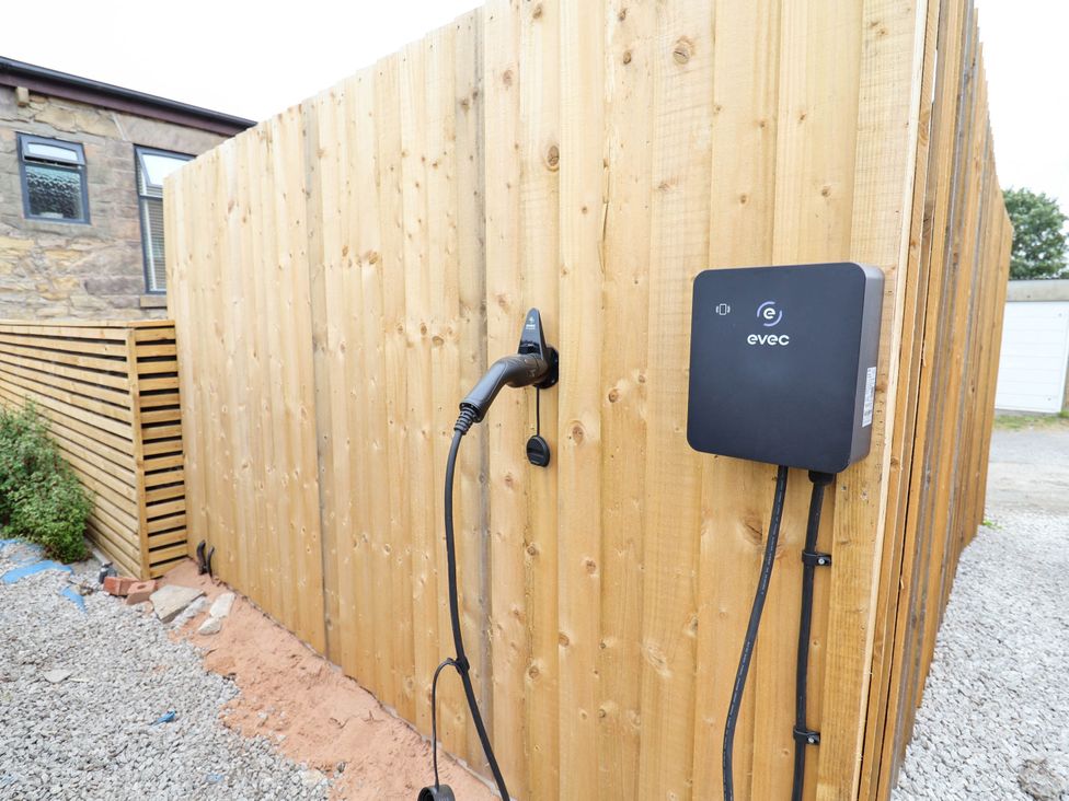 An electric vehicle charging station on a wooden fence at 2 Makant Street Bolton