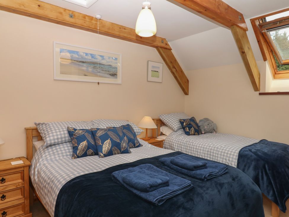 A bedroom with two beds and a bedside table at Brimble Cottage at Dockwell Farm in Newton Abbot