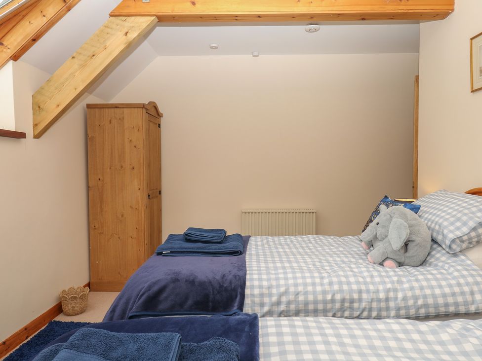 A bedroom with two beds and a wardrobe at Brimble Cottage at Dockwell Farm Newton Abbot