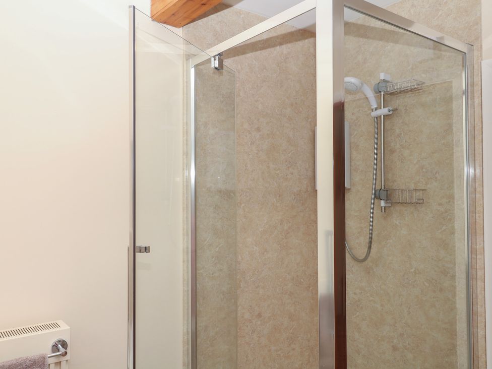 A shower with glass doors and a towel rail at Brimble Cottage at Dockwell Farm Newton Abbot