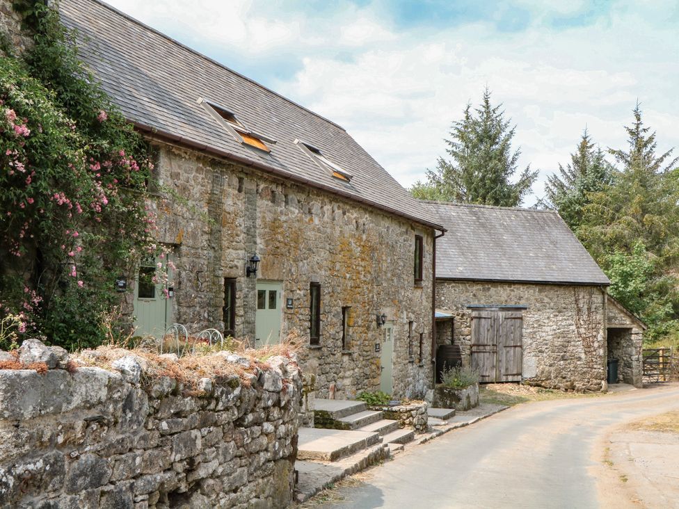 A stone building with flowers and trees at Brimble Cottage at Dockwell Farm in Newton Abbot