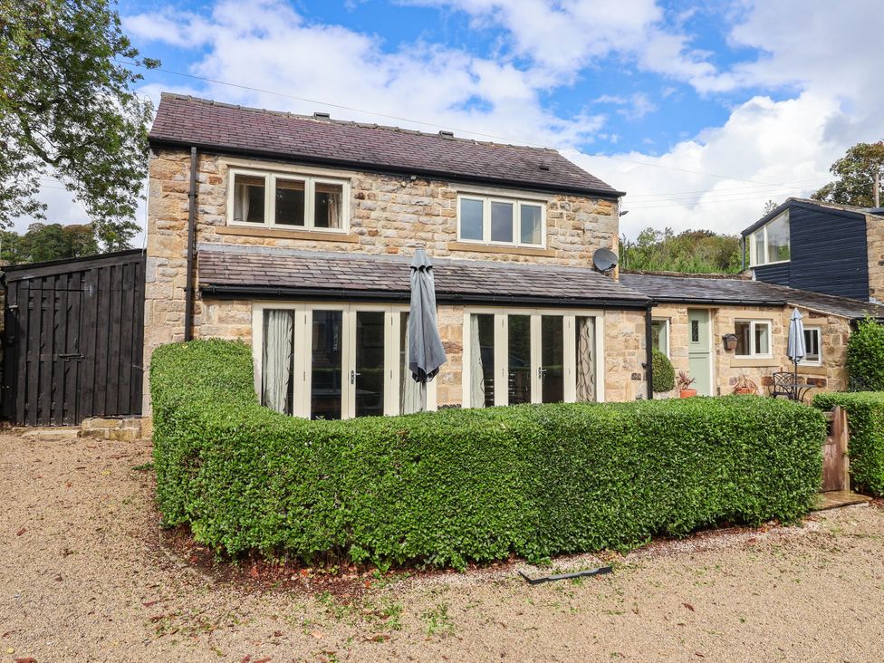 A stone building with windows and a hedge at Honey Pot Cottage in Harrogate