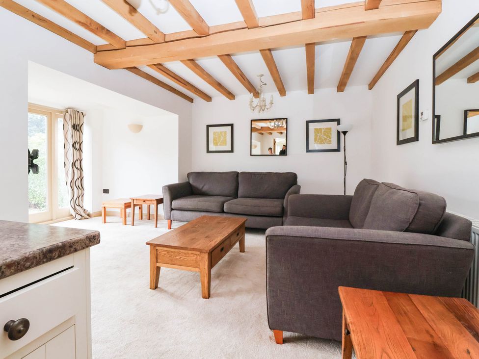 A living room with sofas and wooden tables at Honey Pot Cottage in Harrogate