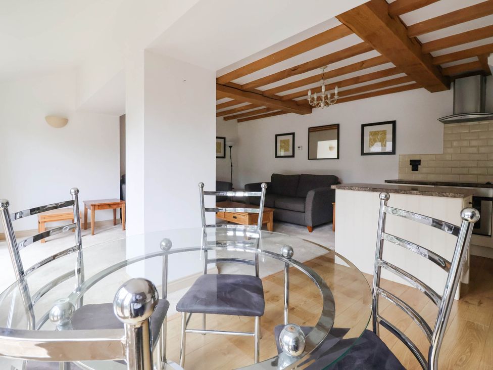 A dining room with a glass table and chairs at Honey Pot Cottage in Harrogate
