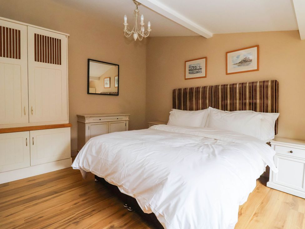 A bedroom with a bed and wardrobe at Honey Pot Cottage in Harrogate