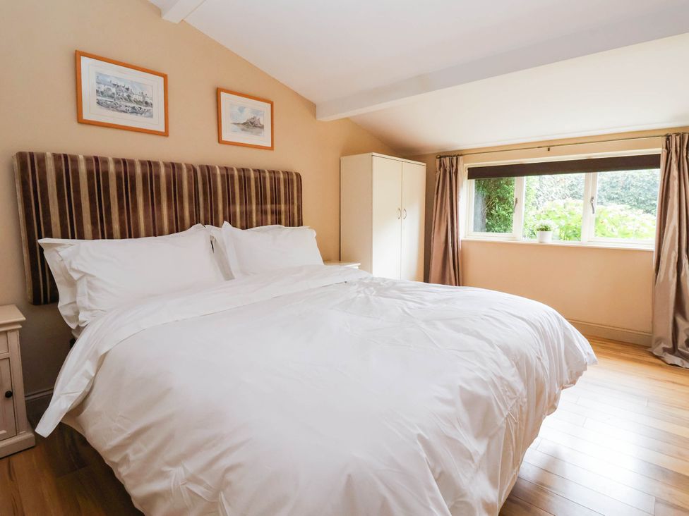 A bedroom with a bed and a cabinet at Honey Pot Cottage in Harrogate