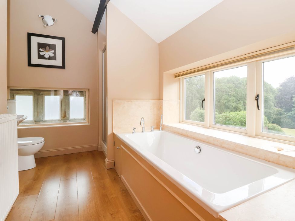 A bathroom featuring a bathtub and a toilet at Honey Pot Cottage in Harrogate
