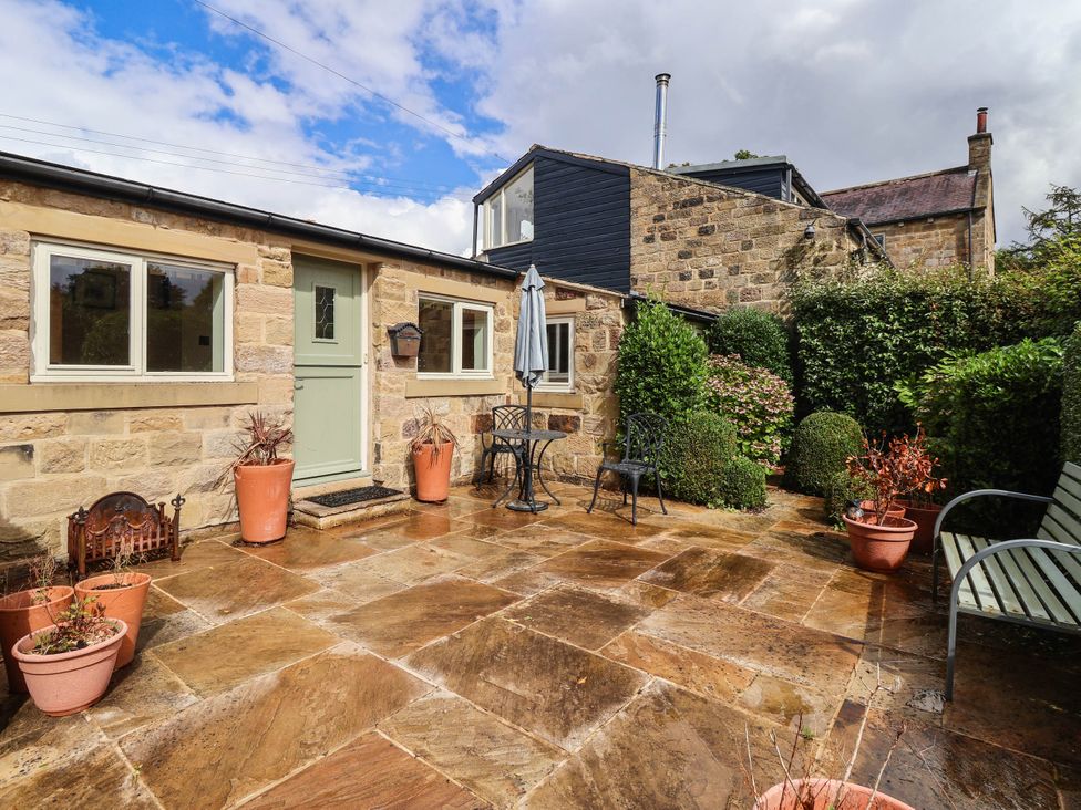 An outdoor patio with seating and potted plants at Honey Pot Cottage in Harrogate