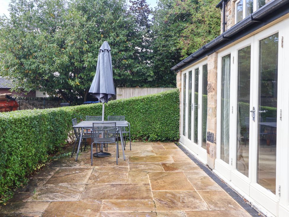 A garden with a patio table and chairs under an umbrella at Honey Pot Cottage in Harrogate