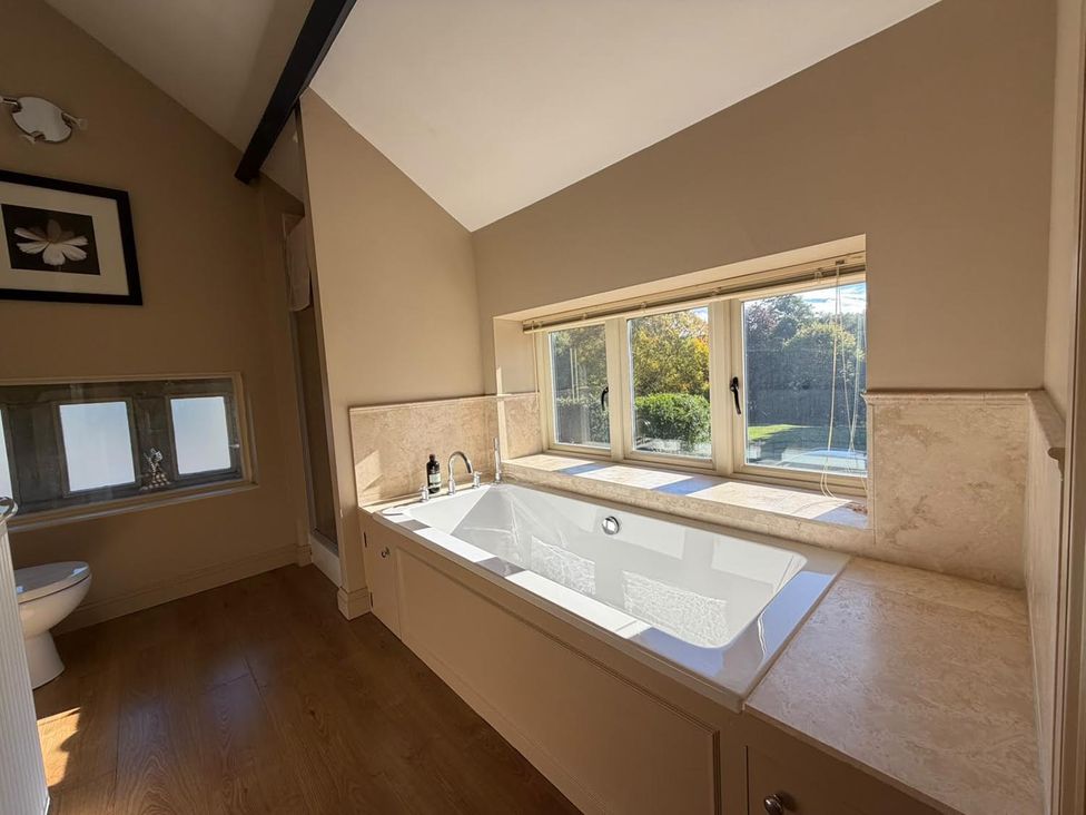 A bathroom with a bathtub and window at Honey Pot Cottage near Harrogate