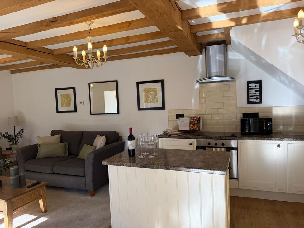 A living room with a sofa and kitchen counter at Honey Pot Cottage near Harrogate