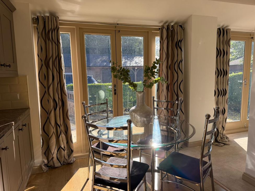 A dining room with a glass table and metal chairs at Honey Pot Cottage near Harrogate