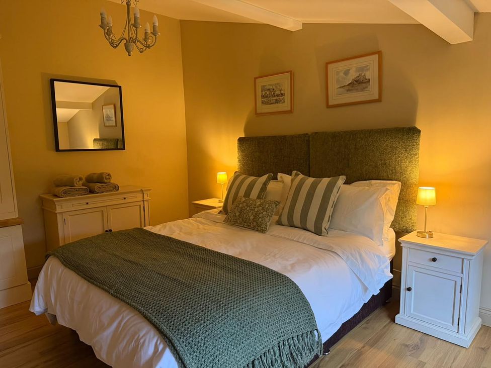 A bedroom with a bed and nightstand at Honey Pot Cottage near Harrogate