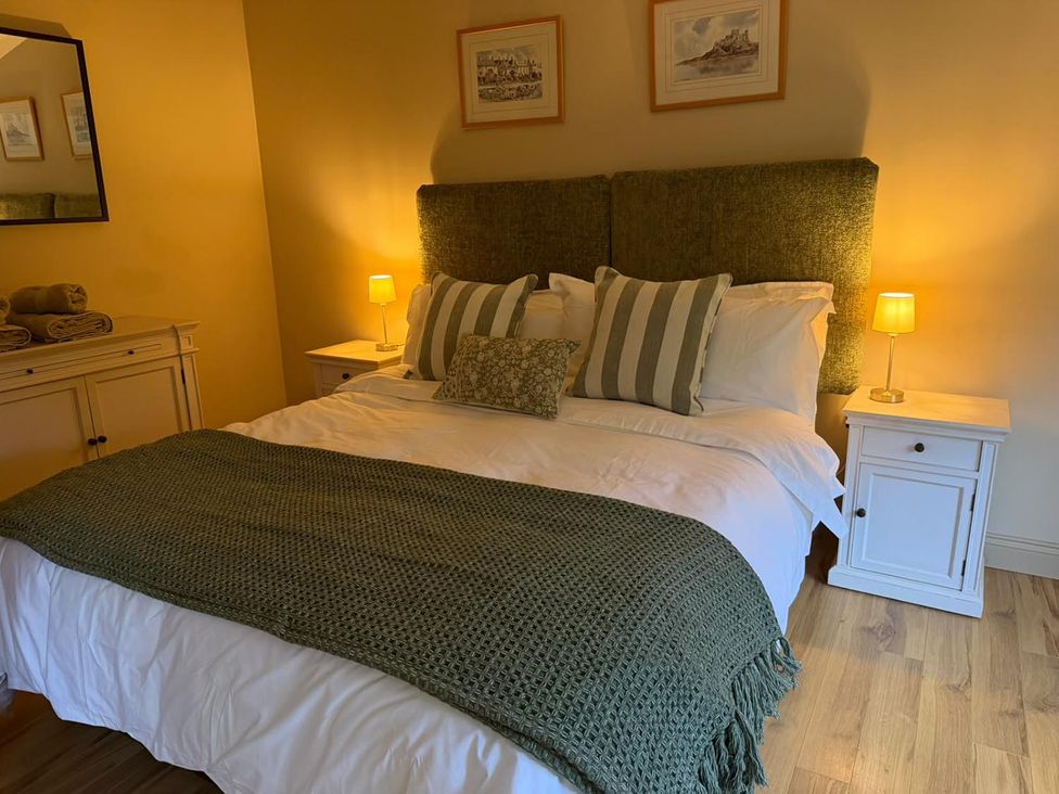 A bedroom with a bed and bedside tables with lamps at Honey Pot Cottage near Harrogate